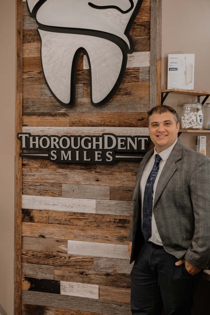 image of Dr. cameron ritz standing beside the logo of thoroughdent smiles