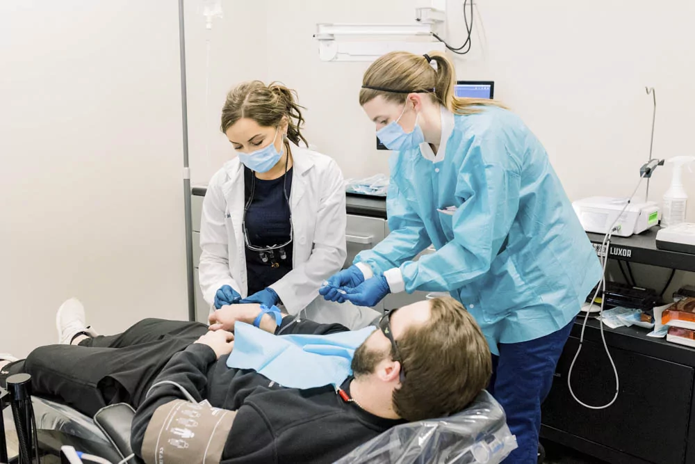 dr neda and dental assistant administering iv sedation to patient
